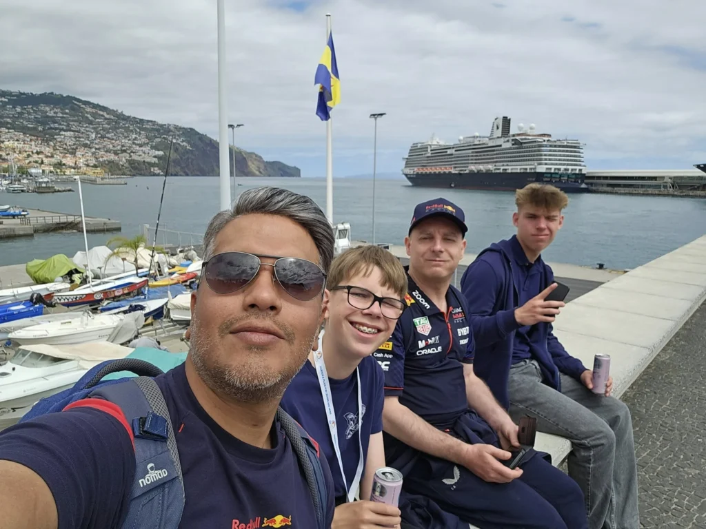 Cruising with Danny and Peter, Holland America Line, Nieuw Statendam, Funchal, Madeira. Portugal, History Adventure | A vibrant collage capturing a day in Funchal, Madeira: a sleek trike navigates winding roads with lush green hills in the background; the panoramic view from Pico dos Barcelos showcases Funchal Bay and the Desertas Islands under a clear sky; Cascata dos Anjos waterfall cascades from cliffs onto a road, surrounded by verdant greenery; Praia da Madalena do Mar’s pebbled beach and black volcanic sand meet gentle waves with towering cliffs above; the misty Valley of the Nuns nestles between rugged mountains, dotted with stone houses and chestnut groves; Cabo Girão’s glass-bottomed skywalk reveals a dizzying drop to the Atlantic and terraced fields below; a plate of warm bolo do caco flatbread filled with steak sits on a café table in Funchal’s colorful old town; the CR7 Museum displays Cristiano Ronaldo’s trophies and jerseys with a waterfront view of the Nieuw Statendam; and Nami Sushi Bar’s elegant sushi platter gleams under soft lighting aboard the ship.