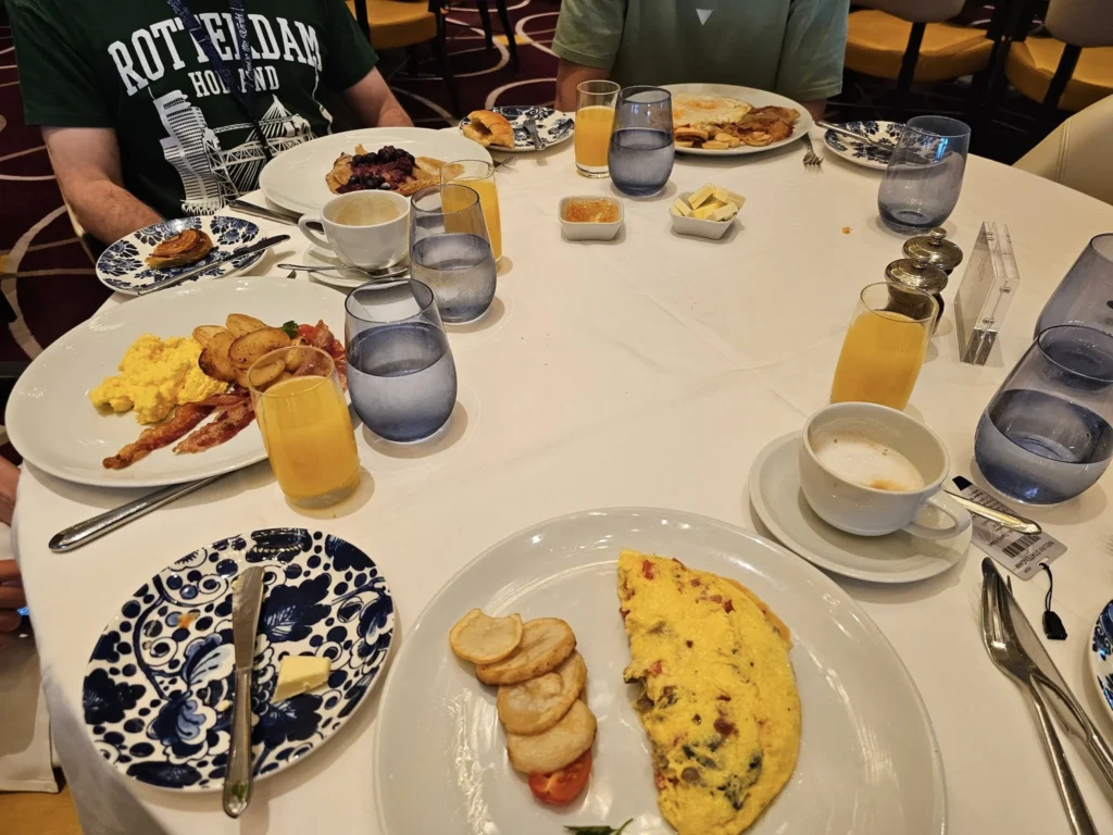 Cruising with Danny and Peter, Holland America Line, Nieuw Statendam, Atlantic Ocean, Sea Day, Adventure | A family savors a Nieuw Statendam Sea Day, enjoying a breakfast of cheesy omelets in the elegant main dining room, indulging in sushi rolls at the vibrant Lido Market, and feasting on a seafood boil with crab legs under starlit skies. The Atlantic Ocean sparkles outside, enhancing Holland America’s luxurious cruise experience with gourmet dining and relaxation.