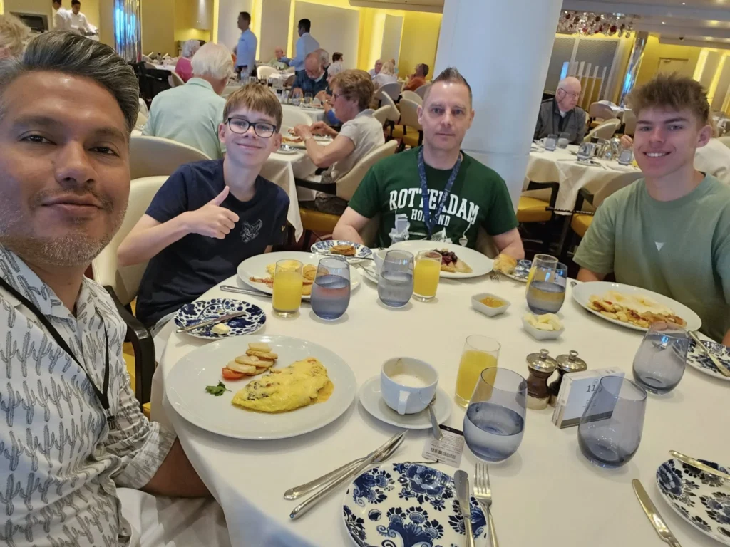 Cruising with Danny and Peter, Holland America Line, Nieuw Statendam, Atlantic Ocean, Sea Day, Adventure | A family savors a Nieuw Statendam Sea Day, enjoying a breakfast of cheesy omelets in the elegant main dining room, indulging in sushi rolls at the vibrant Lido Market, and feasting on a seafood boil with crab legs under starlit skies. The Atlantic Ocean sparkles outside, enhancing Holland America’s luxurious cruise experience with gourmet dining and relaxation.