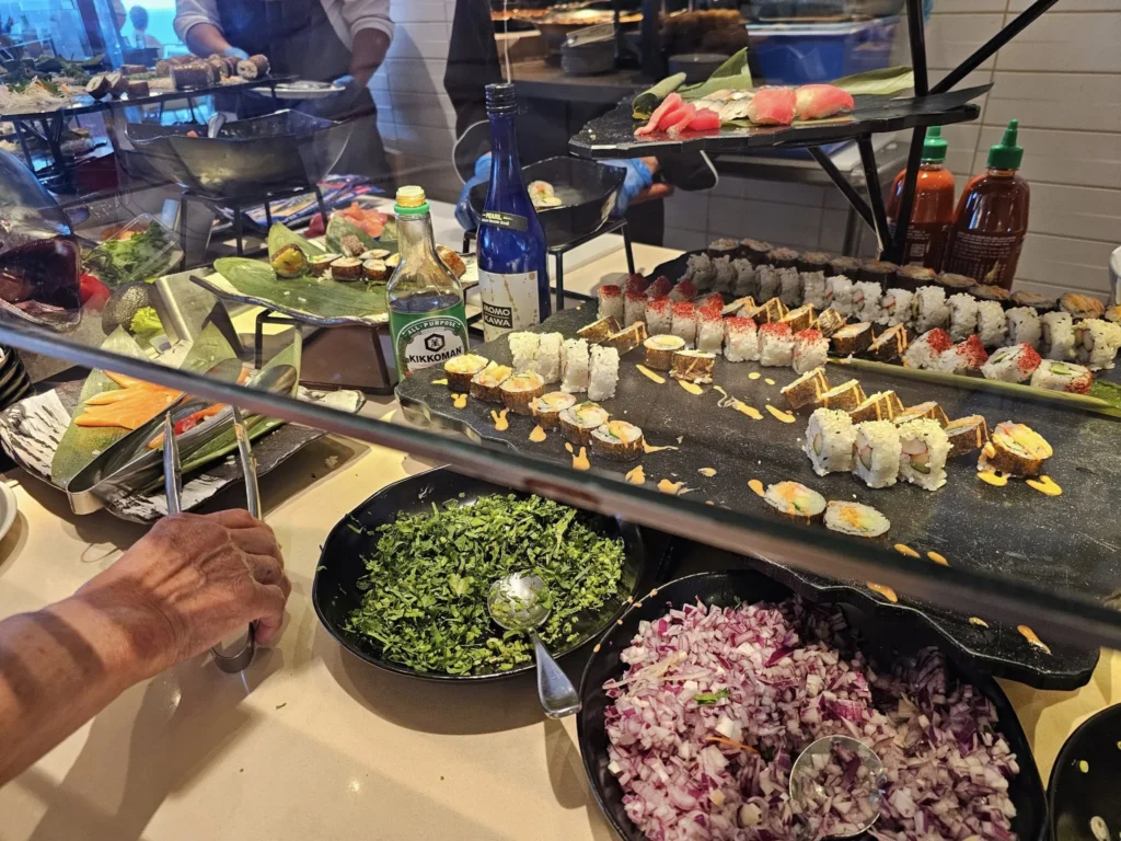 Cruising with Danny and Peter, Holland America Line, Nieuw Statendam, Atlantic Ocean, Sea Day, Adventure | A family savors a Nieuw Statendam Sea Day, enjoying a breakfast of cheesy omelets in the elegant main dining room, indulging in sushi rolls at the vibrant Lido Market, and feasting on a seafood boil with crab legs under starlit skies. The Atlantic Ocean sparkles outside, enhancing Holland America’s luxurious cruise experience with gourmet dining and relaxation.