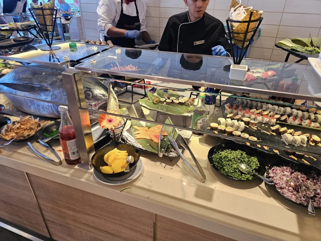 Cruising with Danny and Peter, Holland America Line, Nieuw Statendam, Atlantic Ocean, Sea Day, Adventure | A family savors a Nieuw Statendam Sea Day, enjoying a breakfast of cheesy omelets in the elegant main dining room, indulging in sushi rolls at the vibrant Lido Market, and feasting on a seafood boil with crab legs under starlit skies. The Atlantic Ocean sparkles outside, enhancing Holland America’s luxurious cruise experience with gourmet dining and relaxation.