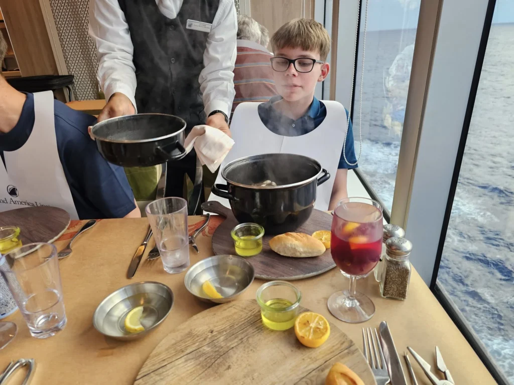 Cruising with Danny and Peter, Holland America Line, Nieuw Statendam, Atlantic Ocean, Sea Day, Adventure | A family savors a Nieuw Statendam Sea Day, enjoying a breakfast of cheesy omelets in the elegant main dining room, indulging in sushi rolls at the vibrant Lido Market, and feasting on a seafood boil with crab legs under starlit skies. The Atlantic Ocean sparkles outside, enhancing Holland America’s luxurious cruise experience with gourmet dining and relaxation.