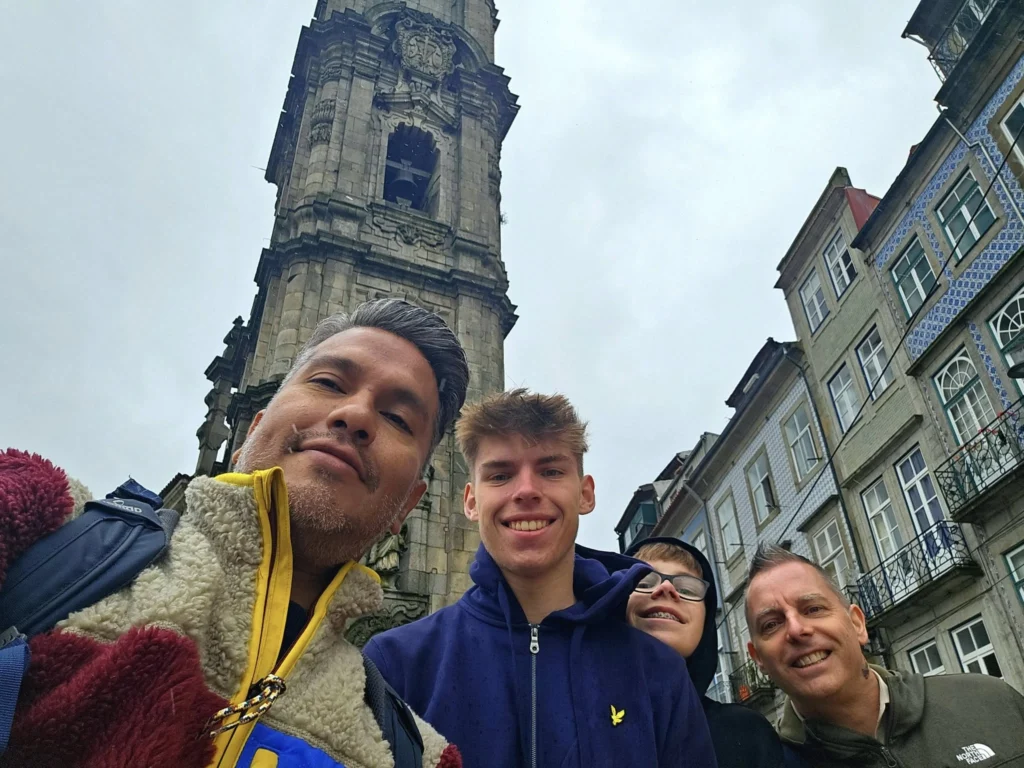 Cruising with Danny and Peter, Holland America Line, Nieuw Statendam, Leixoes, Porto, Portugal, Rainy Adventure | A vibrant collage capturing a rainy day adventure in Porto, Portugal, from the Holland America Line’s Nieuw Statendam cruise. The scene includes a colorful tuk-tuk navigating Porto’s wet, cobblestone streets with historic buildings in the background, the iconic Dom Luís I Bridge spanning the Douro River under gray skies, the majestic Porto Cathedral with its Gothic facade glistening in the rain, and the intricate blue-and-white azulejo tiles of São Bento Station’s atrium. Onboard, a beautifully plated dish from Tamarind restaurant showcases exotic flavors, while the lively Lido Fun Fair on the Lido Midship deck features children enjoying carnival games under a retractable roof, with colorful decorations and cotton candy adding festive cheer.