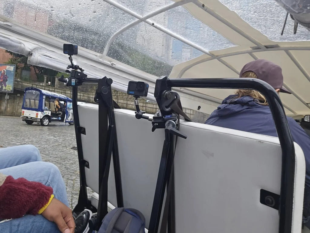 Cruising with Danny and Peter, Holland America Line, Nieuw Statendam, Leixoes, Porto, Portugal, Rainy Adventure | A vibrant collage capturing a rainy day adventure in Porto, Portugal, from the Holland America Line’s Nieuw Statendam cruise. The scene includes a colorful tuk-tuk navigating Porto’s wet, cobblestone streets with historic buildings in the background, the iconic Dom Luís I Bridge spanning the Douro River under gray skies, the majestic Porto Cathedral with its Gothic facade glistening in the rain, and the intricate blue-and-white azulejo tiles of São Bento Station’s atrium. Onboard, a beautifully plated dish from Tamarind restaurant showcases exotic flavors, while the lively Lido Fun Fair on the Lido Midship deck features children enjoying carnival games under a retractable roof, with colorful decorations and cotton candy adding festive cheer.