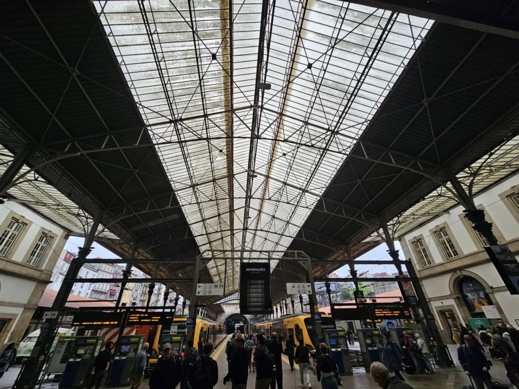 Cruising with Danny and Peter, Holland America Line, Nieuw Statendam, Leixoes, Porto, Portugal, Rainy Adventure | A vibrant collage capturing a rainy day adventure in Porto, Portugal, from the Holland America Line’s Nieuw Statendam cruise. The scene includes a colorful tuk-tuk navigating Porto’s wet, cobblestone streets with historic buildings in the background, the iconic Dom Luís I Bridge spanning the Douro River under gray skies, the majestic Porto Cathedral with its Gothic facade glistening in the rain, and the intricate blue-and-white azulejo tiles of São Bento Station’s atrium. Onboard, a beautifully plated dish from Tamarind restaurant showcases exotic flavors, while the lively Lido Fun Fair on the Lido Midship deck features children enjoying carnival games under a retractable roof, with colorful decorations and cotton candy adding festive cheer.