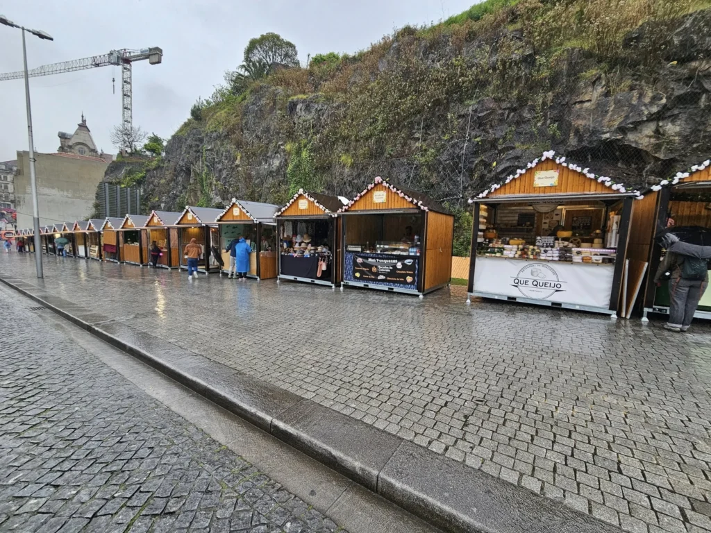 Cruising with Danny and Peter, Holland America Line, Nieuw Statendam, Leixoes, Porto, Portugal, Rainy Adventure | A vibrant collage capturing a rainy day adventure in Porto, Portugal, from the Holland America Line’s Nieuw Statendam cruise. The scene includes a colorful tuk-tuk navigating Porto’s wet, cobblestone streets with historic buildings in the background, the iconic Dom Luís I Bridge spanning the Douro River under gray skies, the majestic Porto Cathedral with its Gothic facade glistening in the rain, and the intricate blue-and-white azulejo tiles of São Bento Station’s atrium. Onboard, a beautifully plated dish from Tamarind restaurant showcases exotic flavors, while the lively Lido Fun Fair on the Lido Midship deck features children enjoying carnival games under a retractable roof, with colorful decorations and cotton candy adding festive cheer.
