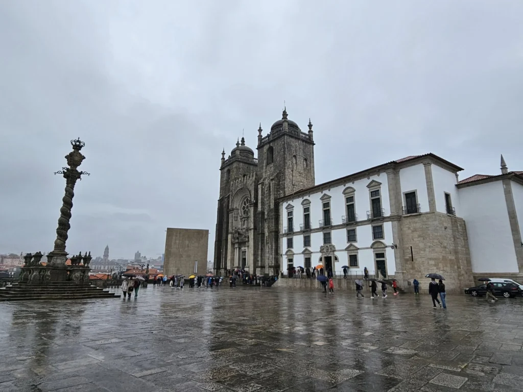 Cruising with Danny and Peter, Holland America Line, Nieuw Statendam, Leixoes, Porto, Portugal, Rainy Adventure | A vibrant collage capturing a rainy day adventure in Porto, Portugal, from the Holland America Line’s Nieuw Statendam cruise. The scene includes a colorful tuk-tuk navigating Porto’s wet, cobblestone streets with historic buildings in the background, the iconic Dom Luís I Bridge spanning the Douro River under gray skies, the majestic Porto Cathedral with its Gothic facade glistening in the rain, and the intricate blue-and-white azulejo tiles of São Bento Station’s atrium. Onboard, a beautifully plated dish from Tamarind restaurant showcases exotic flavors, while the lively Lido Fun Fair on the Lido Midship deck features children enjoying carnival games under a retractable roof, with colorful decorations and cotton candy adding festive cheer.