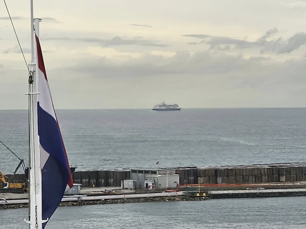 Cruising with Danny and Peter, Holland America Line, Nieuw Statendam, Leixoes, Porto, Portugal, Rainy Adventure | A vibrant collage capturing a rainy day adventure in Porto, Portugal, from the Holland America Line’s Nieuw Statendam cruise. The scene includes a colorful tuk-tuk navigating Porto’s wet, cobblestone streets with historic buildings in the background, the iconic Dom Luís I Bridge spanning the Douro River under gray skies, the majestic Porto Cathedral with its Gothic facade glistening in the rain, and the intricate blue-and-white azulejo tiles of São Bento Station’s atrium. Onboard, a beautifully plated dish from Tamarind restaurant showcases exotic flavors, while the lively Lido Fun Fair on the Lido Midship deck features children enjoying carnival games under a retractable roof, with colorful decorations and cotton candy adding festive cheer.