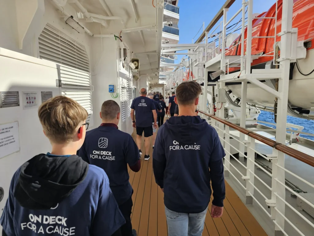 Cruising with Danny and Peter, Holland America Line, Nieuw Statendam, Biscay Bliss Sea Day | A vibrant collage capturing a sea day aboard Holland America Line’s Nieuw Statendam in the Bay of Biscay. The scene includes a pod of dolphins leaping gracefully through shimmering blue waves alongside the ship, their sleek bodies catching the sunlight. Passengers walk energetically on the sunlit deck during a charity event, with the vast ocean horizon stretching behind them. The elegant interior of Rudi’s Sel de Mer restaurant features a beautifully set table with a plate of seared scallops and a chocolate soufflé, illuminated by warm lighting. The World Stage theater glows with a large LED screen displaying Dover’s white cliffs, as the audience listens attentively to a port talk. A couple poses for a photoshoot on deck at sunset, framed by the golden glow of the Bay of Biscay’s horizon, with the ship’s sleek railings in the foreground.