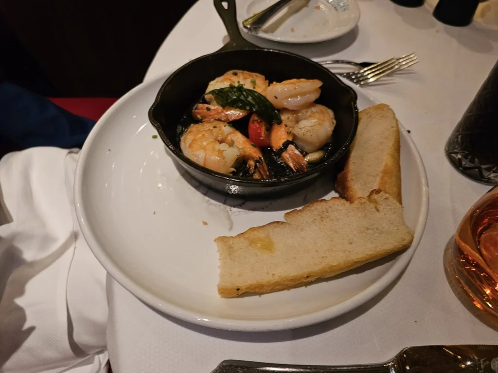 Cruising with Danny and Peter, Holland America Line, Nieuw Statendam, Biscay Bliss Sea Day | A vibrant collage capturing a sea day aboard Holland America Line’s Nieuw Statendam in the Bay of Biscay. The scene includes a pod of dolphins leaping gracefully through shimmering blue waves alongside the ship, their sleek bodies catching the sunlight. Passengers walk energetically on the sunlit deck during a charity event, with the vast ocean horizon stretching behind them. The elegant interior of Rudi’s Sel de Mer restaurant features a beautifully set table with a plate of seared scallops and a chocolate soufflé, illuminated by warm lighting. The World Stage theater glows with a large LED screen displaying Dover’s white cliffs, as the audience listens attentively to a port talk. A couple poses for a photoshoot on deck at sunset, framed by the golden glow of the Bay of Biscay’s horizon, with the ship’s sleek railings in the foreground.