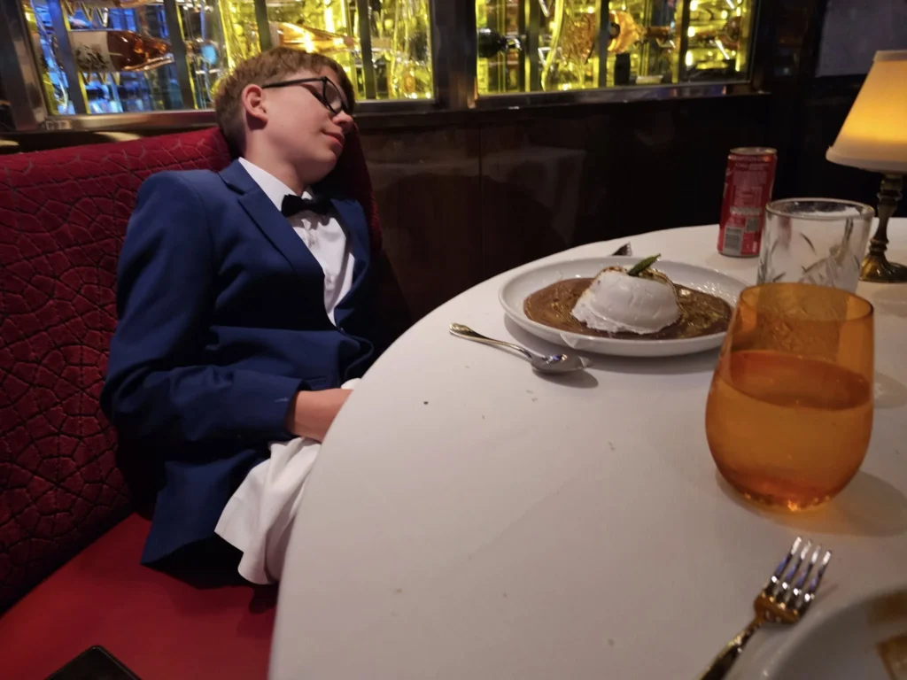 Cruising with Danny and Peter, Holland America Line, Nieuw Statendam, Biscay Bliss Sea Day | A vibrant collage capturing a sea day aboard Holland America Line’s Nieuw Statendam in the Bay of Biscay. The scene includes a pod of dolphins leaping gracefully through shimmering blue waves alongside the ship, their sleek bodies catching the sunlight. Passengers walk energetically on the sunlit deck during a charity event, with the vast ocean horizon stretching behind them. The elegant interior of Rudi’s Sel de Mer restaurant features a beautifully set table with a plate of seared scallops and a chocolate soufflé, illuminated by warm lighting. The World Stage theater glows with a large LED screen displaying Dover’s white cliffs, as the audience listens attentively to a port talk. A couple poses for a photoshoot on deck at sunset, framed by the golden glow of the Bay of Biscay’s horizon, with the ship’s sleek railings in the foreground.