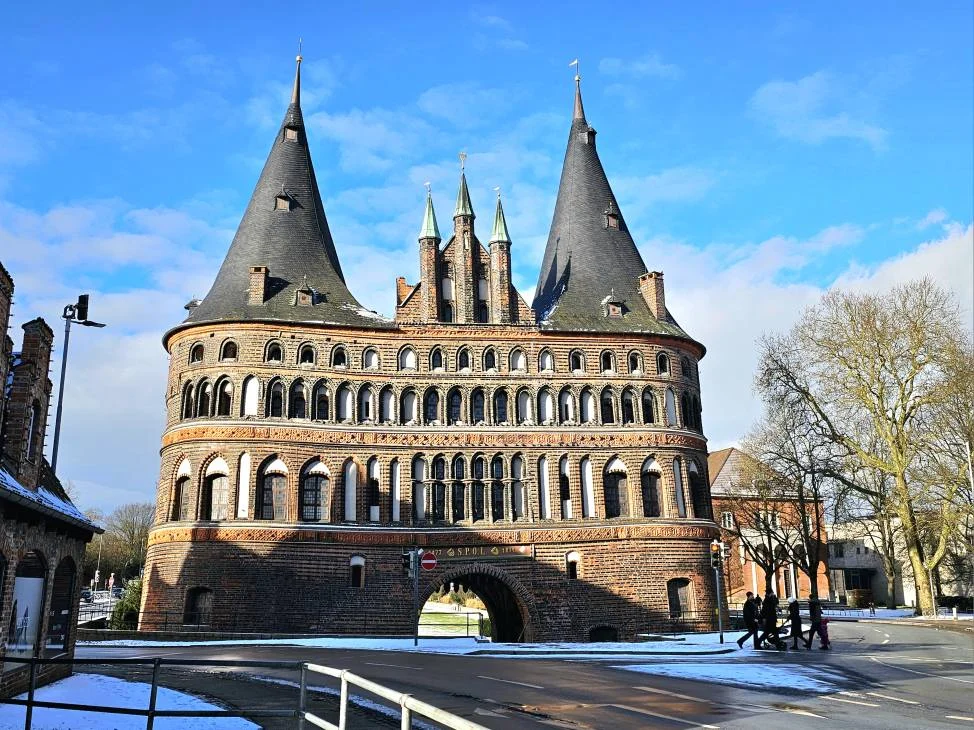 Cruising with Danny and Peter, MSC Cruises, MSC Preziosa, Hamburg, Germany, Lubeck City Tour showcasing the Holsten Gate, a historic medieval landmark with iconic round towers; St. Mary’s Church, known for its Gothic architecture and the world’s largest mechanical organ; charming cobblestone streets and UNESCO Heritage sites of Lubeck, reflecting its Hanseatic League history; traditional German lunch featuring bratwurst, sauerkraut, pretzels, and Lubeck’s famous marzipan, offering a taste of the city’s cultural and culinary heritage.