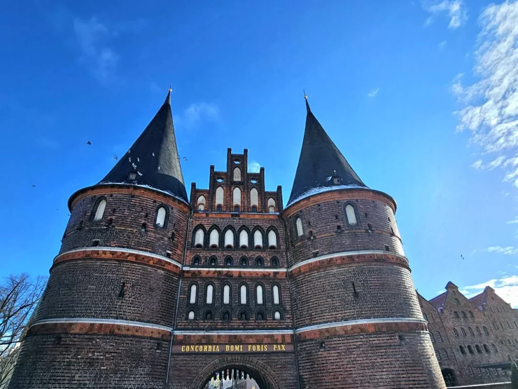 Cruising with Danny and Peter, MSC Cruises, MSC Preziosa, Hamburg, Germany, Lubeck City Tour showcasing the Holsten Gate, a historic medieval landmark with iconic round towers; St. Mary’s Church, known for its Gothic architecture and the world’s largest mechanical organ; charming cobblestone streets and UNESCO Heritage sites of Lubeck, reflecting its Hanseatic League history; traditional German lunch featuring bratwurst, sauerkraut, pretzels, and Lubeck’s famous marzipan, offering a taste of the city’s cultural and culinary heritage.