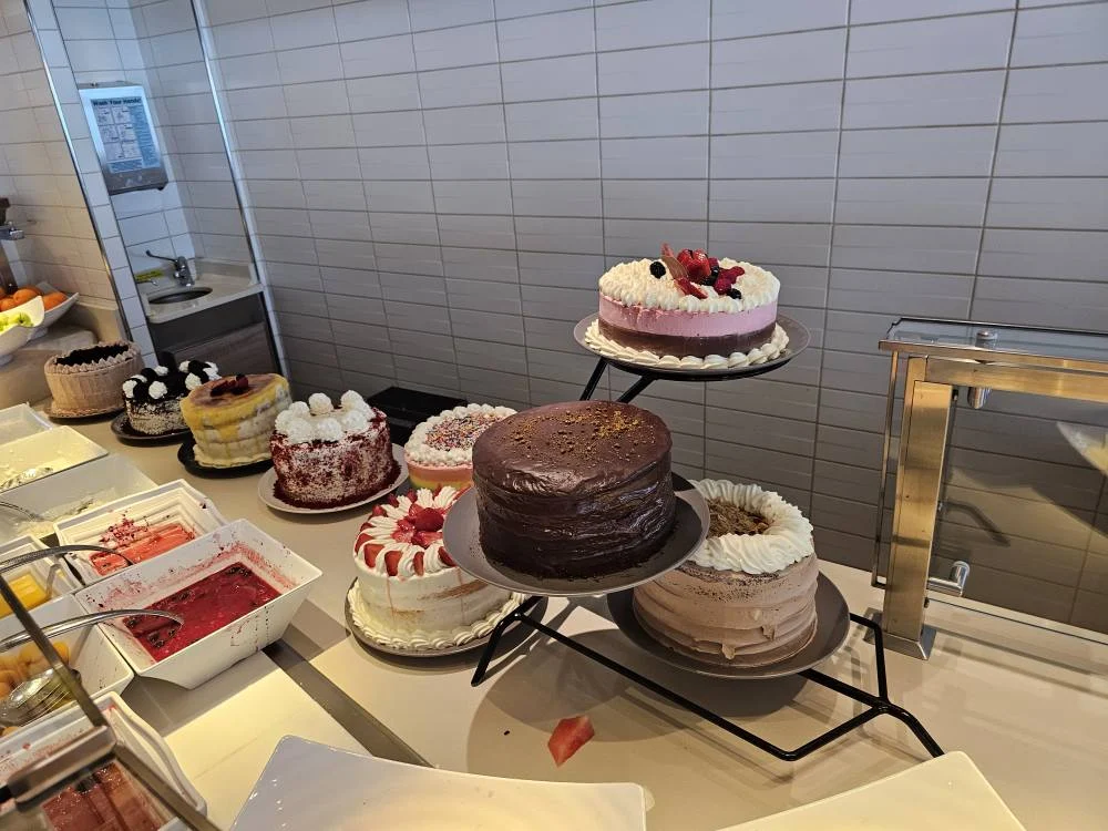 Cruising with Danny and Peter, Holland America Line, Nieuw Statendam, English Channel Sea Day | A montage of a sea day on Holland America’s Nieuw Statendam sailing the English Channel: calm waters meet Dover’s distant white cliffs from a balcony; Sven and Liam play pickleball on a sunlit deck with cheering crowds and a blue sea backdrop; vibrant cakes—chocolate, fruit, and cream-topped—fill the Lido Market as crew serve slices; a candlelit Canaletto table holds Italian dishes in a cozy, rustic dining room.