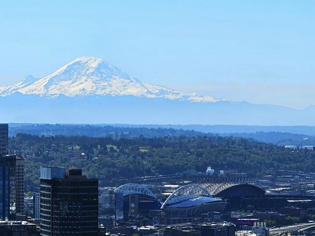 Cruising with Danny and Peter, Holland America Line, Westerdam, Seattle, Washington, United States, Day Trip Arctic Cruise | A vibrant collage capturing a day in Seattle, showcasing Lake Union’s serene waters reflecting the misty skyline with houseboats and kayakers, the towering Space Needle offering panoramic views of Puget Sound and Mount Rainier, and Chihuly Garden and Glass’s colorful glass sculptures blending with lush greenery. Pike Place Market buzzes with vendors tossing salmon and stalls brimming with flowers and artisanal goods under the iconic red sign. A cozy table at Villa Escondida displays tacos al pastor and enchiladas in a warm, mural-lined setting. The Seattle Great Wheel rises above Elliott Bay’s sparkling waterfront, while the Washington Park Arboretum’s tranquil paths feature blooming rhododendrons and a heron by a pond. The Japanese Garden’s koi pond, curved bridge, and stone lanterns create a Zen oasis, all set against Seattle’s dynamic blend of urban and natural beauty.