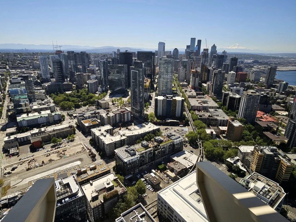 Cruising with Danny and Peter, Holland America Line, Westerdam, Seattle, Washington, United States, Day Trip Arctic Cruise | A vibrant collage capturing a day in Seattle, showcasing Lake Union’s serene waters reflecting the misty skyline with houseboats and kayakers, the towering Space Needle offering panoramic views of Puget Sound and Mount Rainier, and Chihuly Garden and Glass’s colorful glass sculptures blending with lush greenery. Pike Place Market buzzes with vendors tossing salmon and stalls brimming with flowers and artisanal goods under the iconic red sign. A cozy table at Villa Escondida displays tacos al pastor and enchiladas in a warm, mural-lined setting. The Seattle Great Wheel rises above Elliott Bay’s sparkling waterfront, while the Washington Park Arboretum’s tranquil paths feature blooming rhododendrons and a heron by a pond. The Japanese Garden’s koi pond, curved bridge, and stone lanterns create a Zen oasis, all set against Seattle’s dynamic blend of urban and natural beauty.