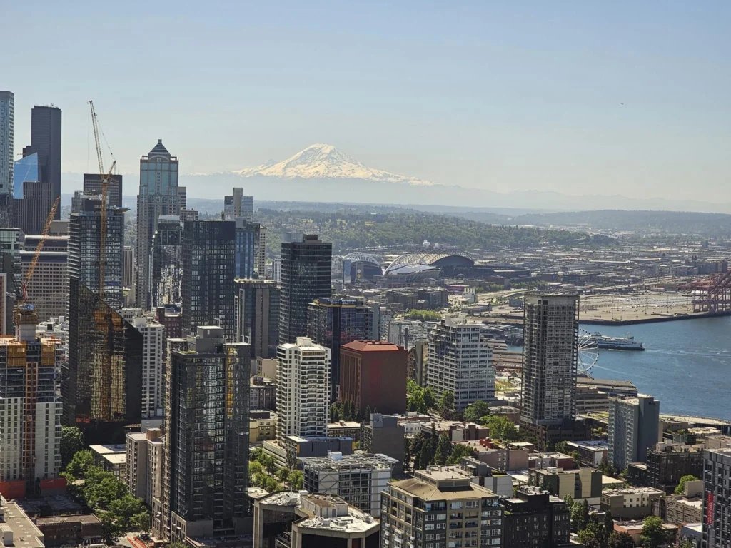Cruising with Danny and Peter, Holland America Line, Westerdam, Seattle, Washington, United States, Day Trip Arctic Cruise | A vibrant collage capturing a day in Seattle, showcasing Lake Union’s serene waters reflecting the misty skyline with houseboats and kayakers, the towering Space Needle offering panoramic views of Puget Sound and Mount Rainier, and Chihuly Garden and Glass’s colorful glass sculptures blending with lush greenery. Pike Place Market buzzes with vendors tossing salmon and stalls brimming with flowers and artisanal goods under the iconic red sign. A cozy table at Villa Escondida displays tacos al pastor and enchiladas in a warm, mural-lined setting. The Seattle Great Wheel rises above Elliott Bay’s sparkling waterfront, while the Washington Park Arboretum’s tranquil paths feature blooming rhododendrons and a heron by a pond. The Japanese Garden’s koi pond, curved bridge, and stone lanterns create a Zen oasis, all set against Seattle’s dynamic blend of urban and natural beauty.