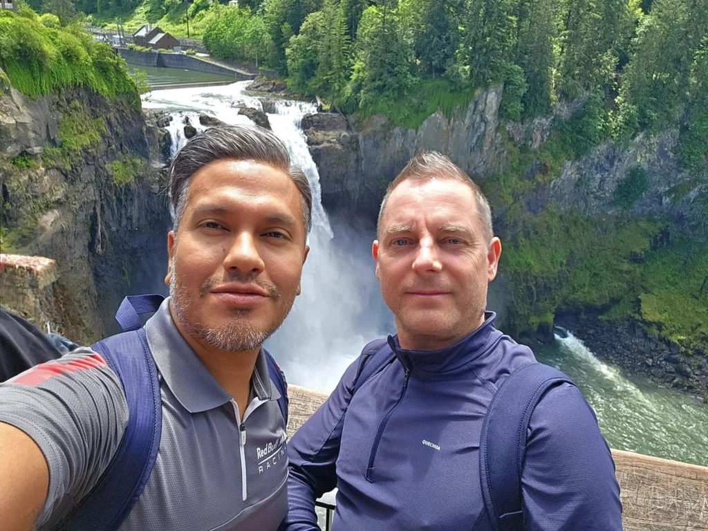 Cruising with Danny and Peter, Holland America Line, Westerdam, Seattle, Washington, United States, Day Trip Waterfalls History | A vibrant collage captures a day in Seattle’s Pacific Northwest Waterfalls Tour, showcasing Pike Place Market’s bustling scene with fishmongers tossing salmon and colorful flower stalls under the iconic red neon sign, set against Puget Sound’s waterfront; Twin Falls cascading over mossy cliffs into a misty pool, surrounded by old-growth evergreens in Olallie State Park, with sunlight filtering through the canopy; North Bend’s retro Twin Peaks diner with its glowing neon sign and quaint main street, framed by rolling hills and the Cascade Mountains; the majestic 270-foot Snoqualmie Falls roaring into a misty pool, with rainbows shimmering in the sunlight and a wooden viewing platform overlooking the lush Snoqualmie Valley; Snoqualmie’s historic district, featuring the Northwest Railway Museum’s vintage locomotives and charming shops lined with old-fashioned street lamps; Borst Lake’s serene waters reflecting Mount Si’s snow-capped peak, with a heron at the edge and evergreen forests under a soft morning mist; and the Museum of Flight’s sleek Concorde and Air Force One jets displayed in a spacious hangar, alongside interactive simulators and a replica of the International Space Station, showcasing Seattle’s aviation heritage.