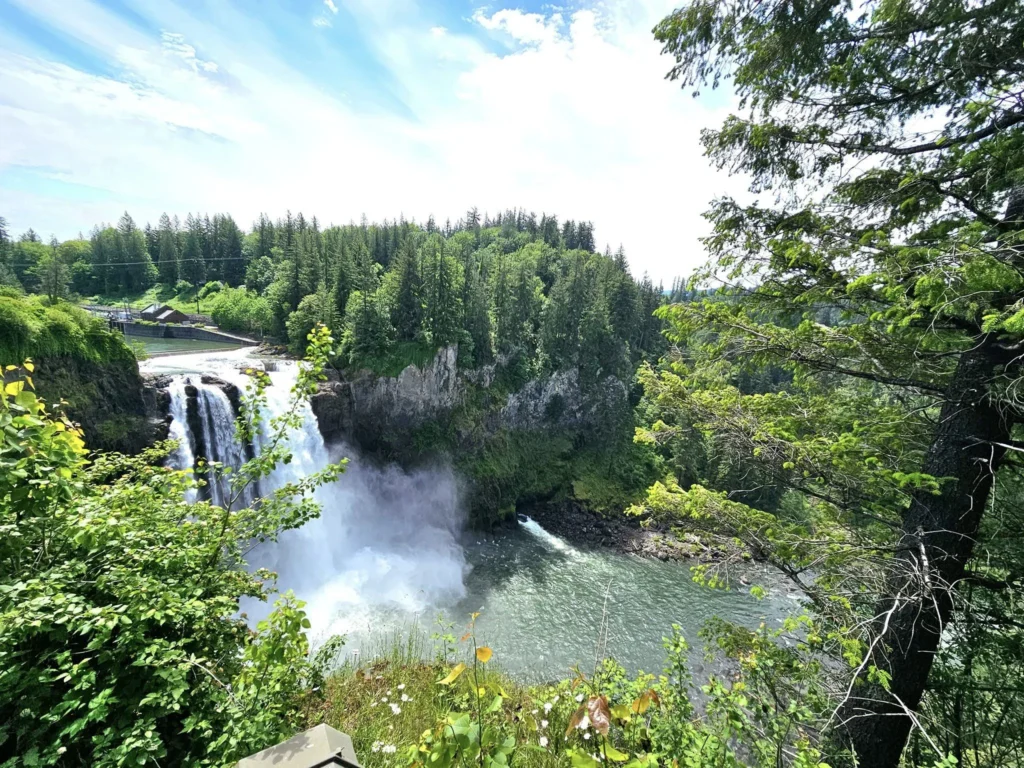 Cruising with Danny and Peter, Holland America Line, Westerdam, Seattle, Washington, United States, Day Trip Waterfalls History | A vibrant collage captures a day in Seattle’s Pacific Northwest Waterfalls Tour, showcasing Pike Place Market’s bustling scene with fishmongers tossing salmon and colorful flower stalls under the iconic red neon sign, set against Puget Sound’s waterfront; Twin Falls cascading over mossy cliffs into a misty pool, surrounded by old-growth evergreens in Olallie State Park, with sunlight filtering through the canopy; North Bend’s retro Twin Peaks diner with its glowing neon sign and quaint main street, framed by rolling hills and the Cascade Mountains; the majestic 270-foot Snoqualmie Falls roaring into a misty pool, with rainbows shimmering in the sunlight and a wooden viewing platform overlooking the lush Snoqualmie Valley; Snoqualmie’s historic district, featuring the Northwest Railway Museum’s vintage locomotives and charming shops lined with old-fashioned street lamps; Borst Lake’s serene waters reflecting Mount Si’s snow-capped peak, with a heron at the edge and evergreen forests under a soft morning mist; and the Museum of Flight’s sleek Concorde and Air Force One jets displayed in a spacious hangar, alongside interactive simulators and a replica of the International Space Station, showcasing Seattle’s aviation heritage.