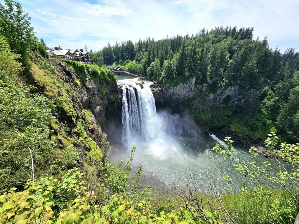 Cruising with Danny and Peter, Holland America Line, Westerdam, Seattle, Washington, United States, Day Trip Waterfalls History | A vibrant collage captures a day in Seattle’s Pacific Northwest Waterfalls Tour, showcasing Pike Place Market’s bustling scene with fishmongers tossing salmon and colorful flower stalls under the iconic red neon sign, set against Puget Sound’s waterfront; Twin Falls cascading over mossy cliffs into a misty pool, surrounded by old-growth evergreens in Olallie State Park, with sunlight filtering through the canopy; North Bend’s retro Twin Peaks diner with its glowing neon sign and quaint main street, framed by rolling hills and the Cascade Mountains; the majestic 270-foot Snoqualmie Falls roaring into a misty pool, with rainbows shimmering in the sunlight and a wooden viewing platform overlooking the lush Snoqualmie Valley; Snoqualmie’s historic district, featuring the Northwest Railway Museum’s vintage locomotives and charming shops lined with old-fashioned street lamps; Borst Lake’s serene waters reflecting Mount Si’s snow-capped peak, with a heron at the edge and evergreen forests under a soft morning mist; and the Museum of Flight’s sleek Concorde and Air Force One jets displayed in a spacious hangar, alongside interactive simulators and a replica of the International Space Station, showcasing Seattle’s aviation heritage.