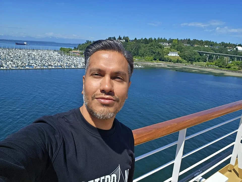 Cruising with Danny and Peter, Holland America Line, Westerdam, Seattle, Washington, United States, Alaska Solstice Cruise | A vibrant scene captures the Holland America Line’s Westerdam docked at Pier 91 in Seattle, Washington, with the iconic Space Needle and bustling Pike Place Market visible in the background, ready for the 28-Day Alaska Arctic Circle Solstice Cruise. The image showcases passengers excitedly boarding the ship, the luxurious stateroom with a spacious balcony offering stunning views of Elliott Bay, and the vessel setting sail from Seattle, marking the start of an unforgettable Alaskan adventure.