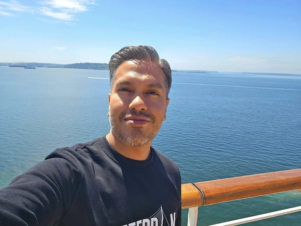 Cruising with Danny and Peter, Holland America Line, Westerdam, Seattle, Washington, United States, Alaska Solstice Cruise | A vibrant scene captures the Holland America Line’s Westerdam docked at Pier 91 in Seattle, Washington, with the iconic Space Needle and bustling Pike Place Market visible in the background, ready for the 28-Day Alaska Arctic Circle Solstice Cruise. The image showcases passengers excitedly boarding the ship, the luxurious stateroom with a spacious balcony offering stunning views of Elliott Bay, and the vessel setting sail from Seattle, marking the start of an unforgettable Alaskan adventure.