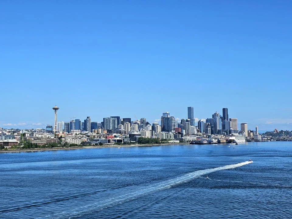 Cruising with Danny and Peter, Holland America Line, Westerdam, Seattle, Washington, United States, Alaska Solstice Cruise | A vibrant scene captures the Holland America Line’s Westerdam docked at Pier 91 in Seattle, Washington, with the iconic Space Needle and bustling Pike Place Market visible in the background, ready for the 28-Day Alaska Arctic Circle Solstice Cruise. The image showcases passengers excitedly boarding the ship, the luxurious stateroom with a spacious balcony offering stunning views of Elliott Bay, and the vessel setting sail from Seattle, marking the start of an unforgettable Alaskan adventure.