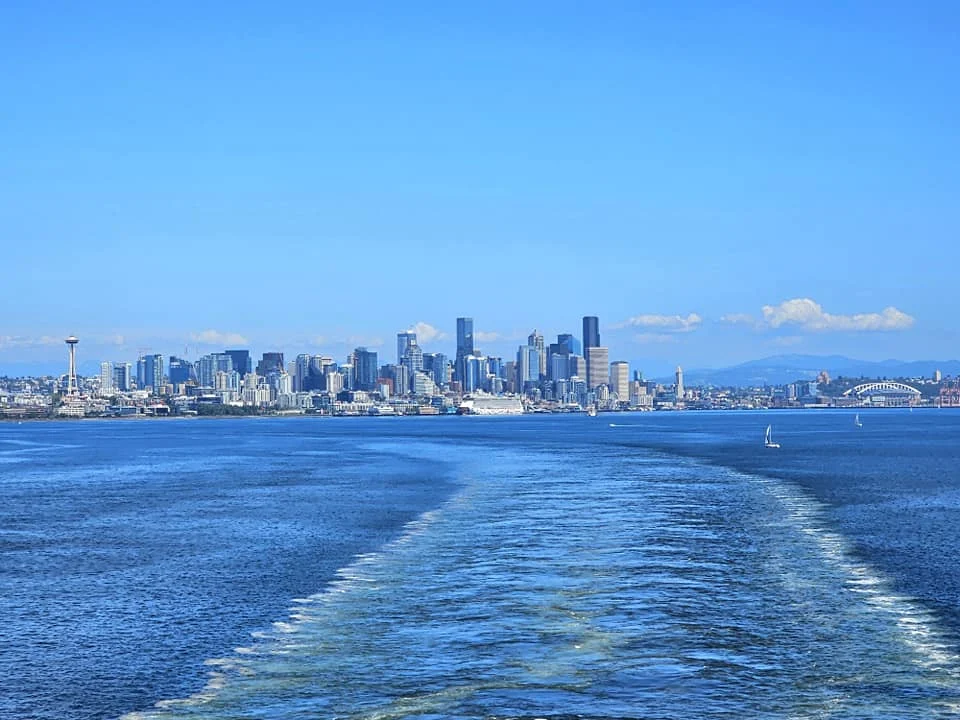 Cruising with Danny and Peter, Holland America Line, Westerdam, Seattle, Washington, United States, Alaska Solstice Cruise | A vibrant scene captures the Holland America Line’s Westerdam docked at Pier 91 in Seattle, Washington, with the iconic Space Needle and bustling Pike Place Market visible in the background, ready for the 28-Day Alaska Arctic Circle Solstice Cruise. The image showcases passengers excitedly boarding the ship, the luxurious stateroom with a spacious balcony offering stunning views of Elliott Bay, and the vessel setting sail from Seattle, marking the start of an unforgettable Alaskan adventure.