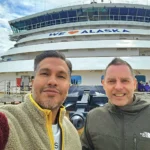 Cruising with Danny and Peter, Holland America Line, Westerdam, Inside Passage, Alaska, United States | Westerdam luxury cruise ship sailing through the Inside Passage, with majestic glaciers and dramatic landscapes in view. The image features an elegant stateroom with a spacious veranda, offering panoramic scenery, and highlights gourmet dining and an informative lecture by onboard naturalists, showcasing the comprehensive luxury and educational experience of the cruise.