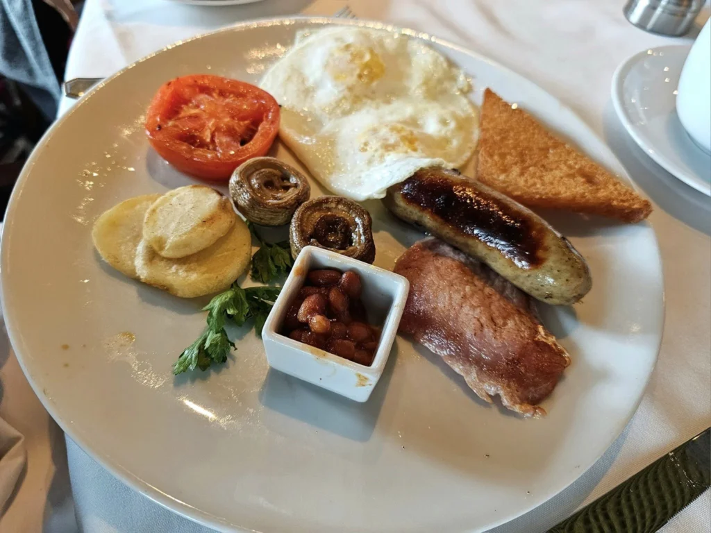 Cruising with Danny and Peter, Holland America Line, Westerdam, Inside Passage, Alaska, United States | Westerdam luxury cruise ship sailing through the Inside Passage, with majestic glaciers and dramatic landscapes in view. The image features an elegant stateroom with a spacious veranda, offering panoramic scenery, and highlights gourmet dining and an informative lecture by onboard naturalists, showcasing the comprehensive luxury and educational experience of the cruise.