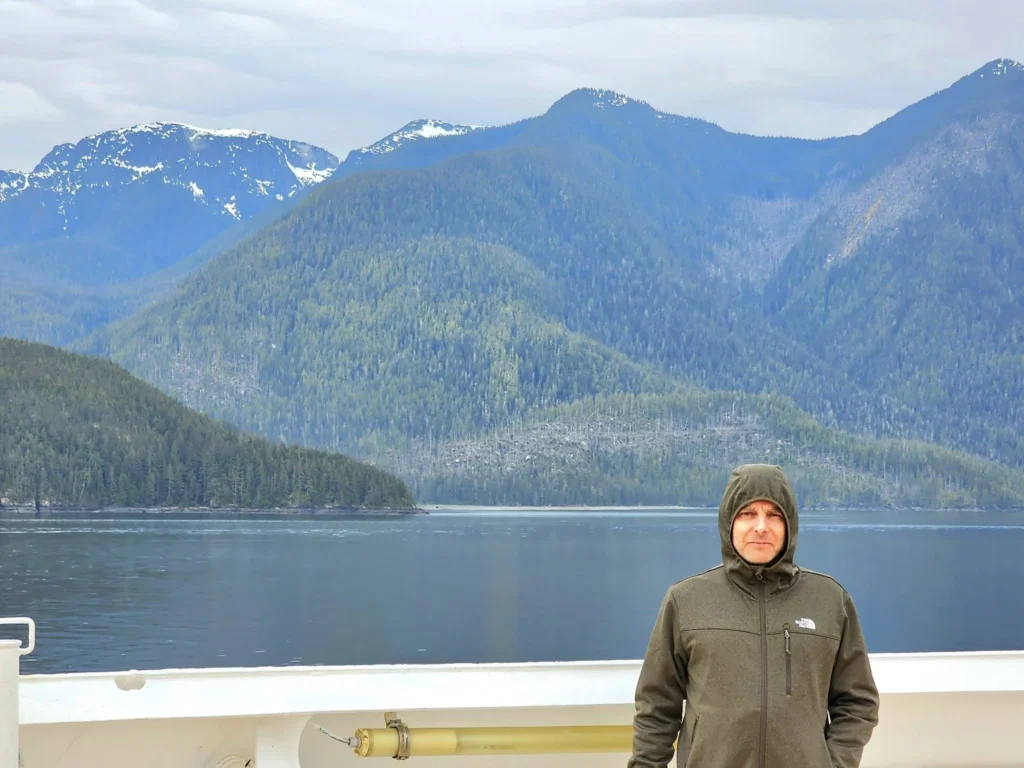 Cruising with Danny and Peter, Holland America Line, Westerdam, Inside Passage, Alaska, United States | Westerdam luxury cruise ship sailing through the Inside Passage, with majestic glaciers and dramatic landscapes in view. The image features an elegant stateroom with a spacious veranda, offering panoramic scenery, and highlights gourmet dining and an informative lecture by onboard naturalists, showcasing the comprehensive luxury and educational experience of the cruise.