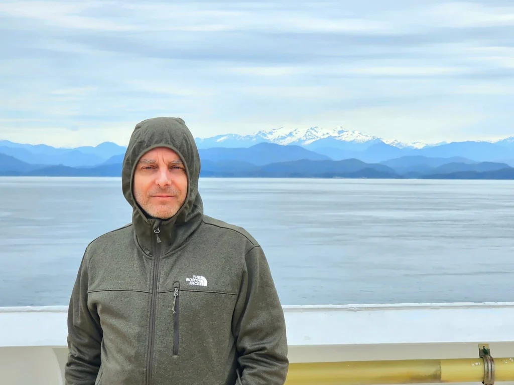 Cruising with Danny and Peter, Holland America Line, Westerdam, Inside Passage, Alaska, United States | Westerdam luxury cruise ship sailing through the Inside Passage, with majestic glaciers and dramatic landscapes in view. The image features an elegant stateroom with a spacious veranda, offering panoramic scenery, and highlights gourmet dining and an informative lecture by onboard naturalists, showcasing the comprehensive luxury and educational experience of the cruise.