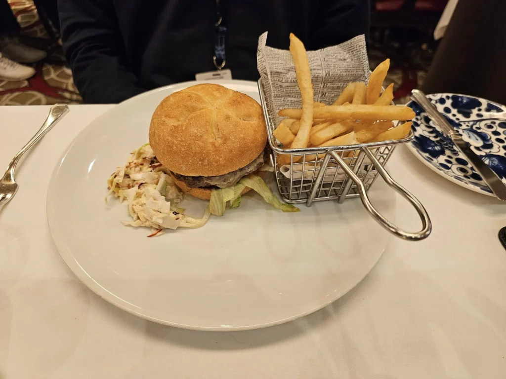 Cruising with Danny and Peter, Holland America Line, Westerdam, Inside Passage, Alaska, United States | Westerdam luxury cruise ship sailing through the Inside Passage, with majestic glaciers and dramatic landscapes in view. The image features an elegant stateroom with a spacious veranda, offering panoramic scenery, and highlights gourmet dining and an informative lecture by onboard naturalists, showcasing the comprehensive luxury and educational experience of the cruise.