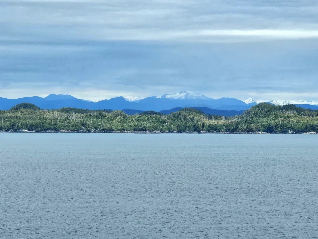 Cruising with Danny and Peter, Holland America Line, Westerdam, Inside Passage, Alaska, United States | Westerdam luxury cruise ship sailing through the Inside Passage, with majestic glaciers and dramatic landscapes in view. The image features an elegant stateroom with a spacious veranda, offering panoramic scenery, and highlights gourmet dining and an informative lecture by onboard naturalists, showcasing the comprehensive luxury and educational experience of the cruise.