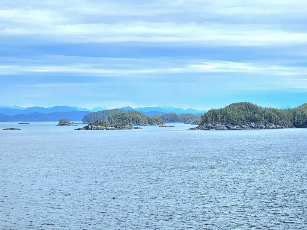 Cruising with Danny and Peter, Holland America Line, Westerdam, Inside Passage, Alaska, United States | Westerdam luxury cruise ship sailing through the Inside Passage, with majestic glaciers and dramatic landscapes in view. The image features an elegant stateroom with a spacious veranda, offering panoramic scenery, and highlights gourmet dining and an informative lecture by onboard naturalists, showcasing the comprehensive luxury and educational experience of the cruise.