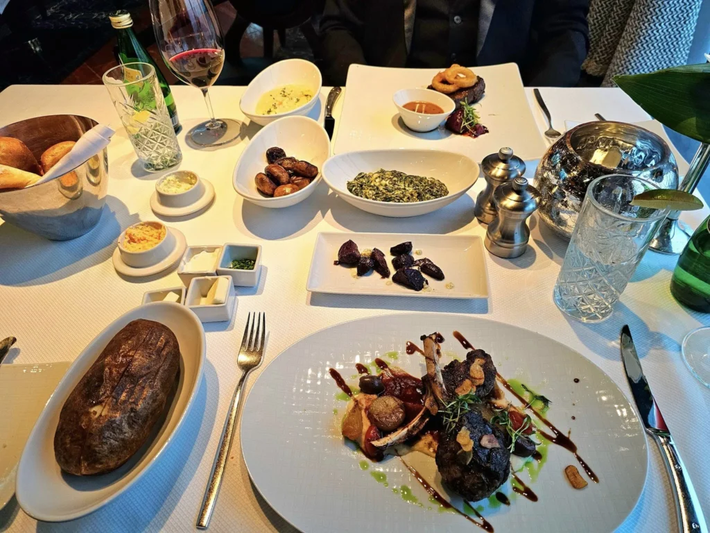 Cruising with Danny and Peter, Holland America Line, Westerdam, Inside Passage, Alaska, United States | Westerdam luxury cruise ship sailing through the Inside Passage, with majestic glaciers and dramatic landscapes in view. The image features an elegant stateroom with a spacious veranda, offering panoramic scenery, and highlights gourmet dining and an informative lecture by onboard naturalists, showcasing the comprehensive luxury and educational experience of the cruise.