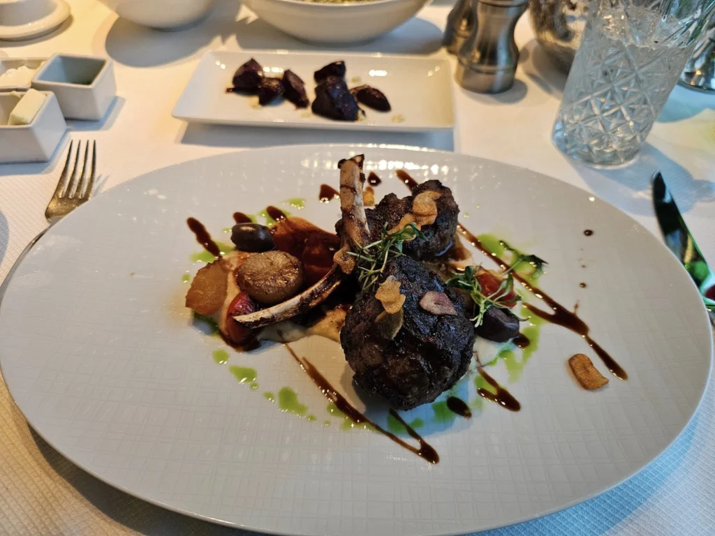 Cruising with Danny and Peter, Holland America Line, Westerdam, Inside Passage, Alaska, United States | Westerdam luxury cruise ship sailing through the Inside Passage, with majestic glaciers and dramatic landscapes in view. The image features an elegant stateroom with a spacious veranda, offering panoramic scenery, and highlights gourmet dining and an informative lecture by onboard naturalists, showcasing the comprehensive luxury and educational experience of the cruise.