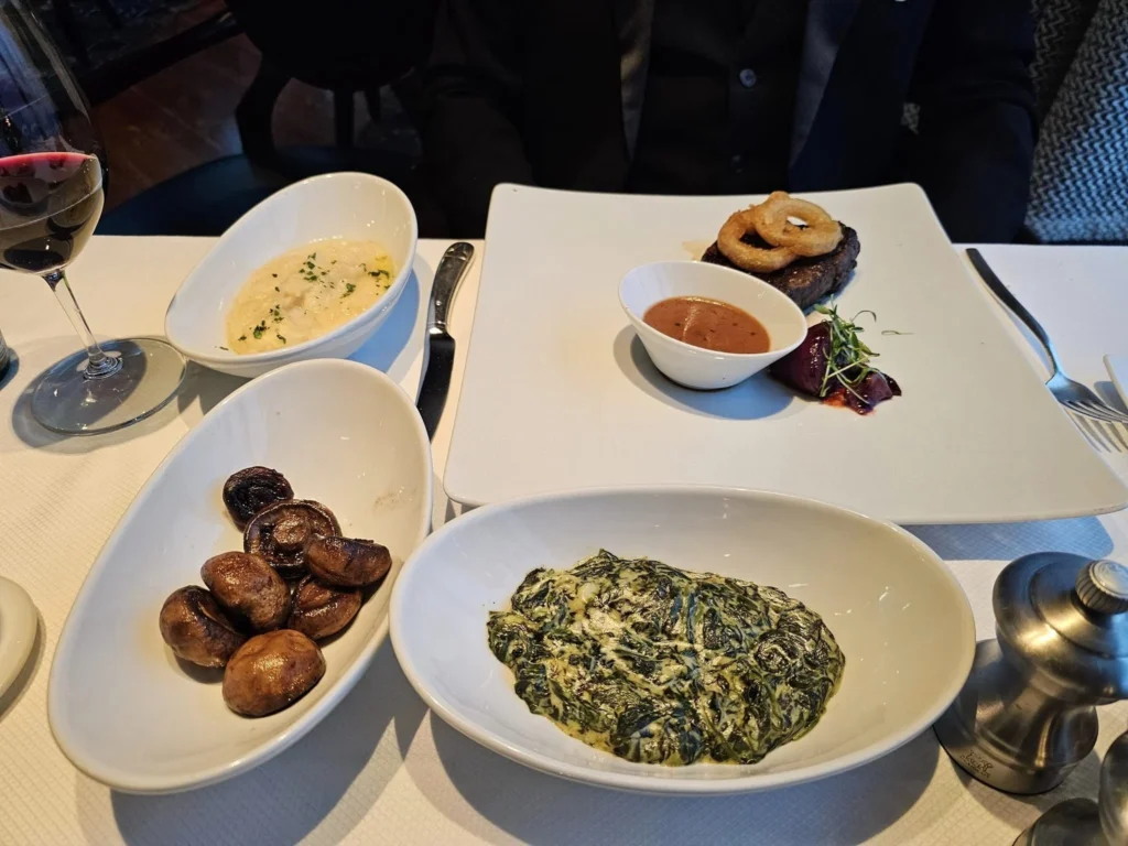 Cruising with Danny and Peter, Holland America Line, Westerdam, Inside Passage, Alaska, United States | Westerdam luxury cruise ship sailing through the Inside Passage, with majestic glaciers and dramatic landscapes in view. The image features an elegant stateroom with a spacious veranda, offering panoramic scenery, and highlights gourmet dining and an informative lecture by onboard naturalists, showcasing the comprehensive luxury and educational experience of the cruise.