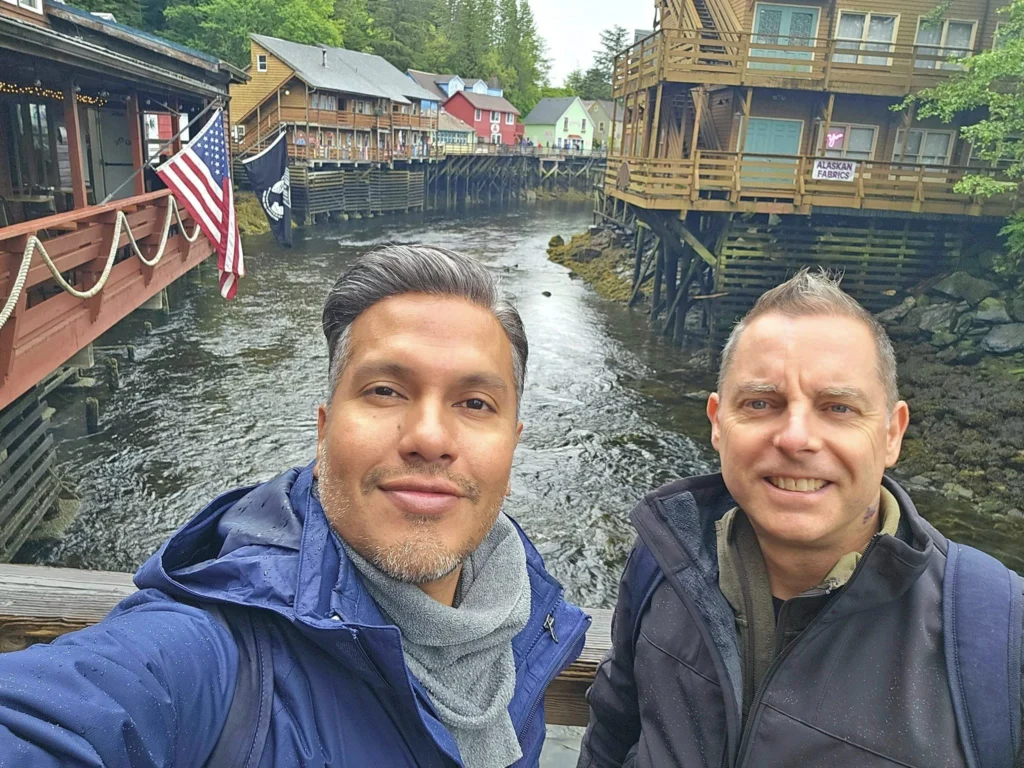 Cruising with Danny and Peter, Holland America Line, Westerdam, Ketchikan, Alaska, United States, Adventure History Thrills | A vibrant collage capturing the Ketchikan Adventure Tour in Alaska, featuring a dynamic log-rolling contest at the Great Alaskan Lumberjack Show with lumberjacks in plaid shirts balancing on a floating log, a rugged UTV navigating a muddy trail through the Tongass National Forest with George Inlet Fjords’ turquoise waters in view, a serene scenic cruise along the Inside Passage with a bald eagle soaring above mist-covered mountains, and a cozy scene at George Inlet Lodge with a rustic table set with craft beers, creamy crab chowder, hot Dungeness crab, and blueberry cheesecake. In the background, Ketchikan’s historic Creek Street showcases colorful buildings on stilts and a Tlingit totem pole, framed by lush greenery and rugged Alaskan peaks, embodying the city’s thrilling adventures and rich cultural heritage.