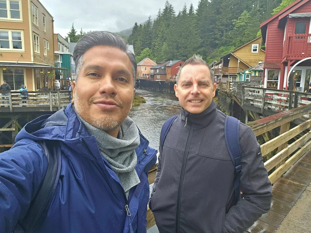 Cruising with Danny and Peter, Holland America Line, Westerdam, Ketchikan, Alaska, United States, Adventure History Thrills | A vibrant collage capturing the Ketchikan Adventure Tour in Alaska, featuring a dynamic log-rolling contest at the Great Alaskan Lumberjack Show with lumberjacks in plaid shirts balancing on a floating log, a rugged UTV navigating a muddy trail through the Tongass National Forest with George Inlet Fjords’ turquoise waters in view, a serene scenic cruise along the Inside Passage with a bald eagle soaring above mist-covered mountains, and a cozy scene at George Inlet Lodge with a rustic table set with craft beers, creamy crab chowder, hot Dungeness crab, and blueberry cheesecake. In the background, Ketchikan’s historic Creek Street showcases colorful buildings on stilts and a Tlingit totem pole, framed by lush greenery and rugged Alaskan peaks, embodying the city’s thrilling adventures and rich cultural heritage.