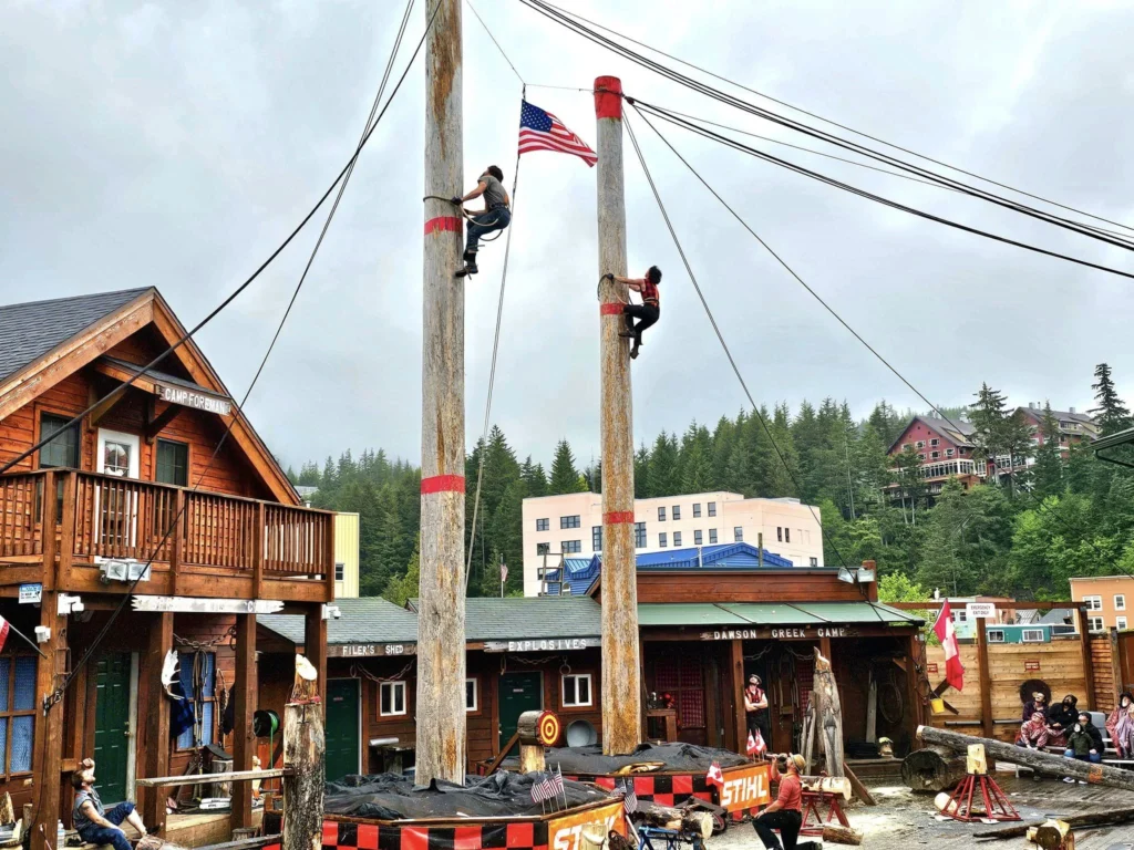 Cruising with Danny and Peter, Holland America Line, Westerdam, Ketchikan, Alaska, United States, Adventure History Thrills | A vibrant collage capturing the Ketchikan Adventure Tour in Alaska, featuring a dynamic log-rolling contest at the Great Alaskan Lumberjack Show with lumberjacks in plaid shirts balancing on a floating log, a rugged UTV navigating a muddy trail through the Tongass National Forest with George Inlet Fjords’ turquoise waters in view, a serene scenic cruise along the Inside Passage with a bald eagle soaring above mist-covered mountains, and a cozy scene at George Inlet Lodge with a rustic table set with craft beers, creamy crab chowder, hot Dungeness crab, and blueberry cheesecake. In the background, Ketchikan’s historic Creek Street showcases colorful buildings on stilts and a Tlingit totem pole, framed by lush greenery and rugged Alaskan peaks, embodying the city’s thrilling adventures and rich cultural heritage.