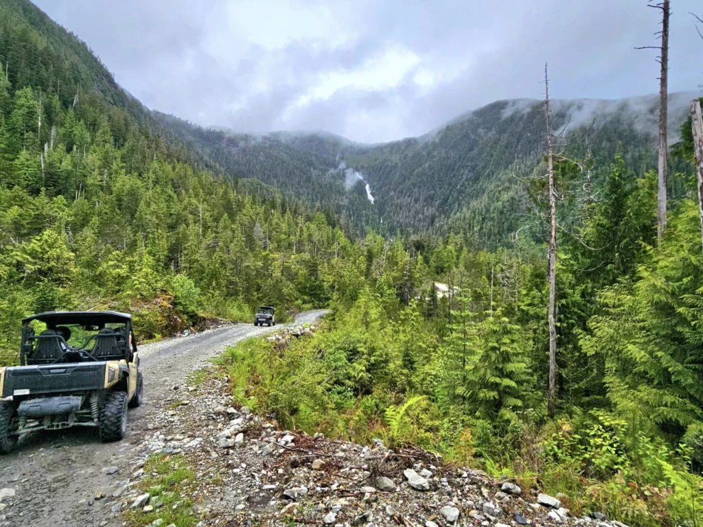 Cruising with Danny and Peter, Holland America Line, Westerdam, Ketchikan, Alaska, United States, Adventure History Thrills | A vibrant collage capturing the Ketchikan Adventure Tour in Alaska, featuring a dynamic log-rolling contest at the Great Alaskan Lumberjack Show with lumberjacks in plaid shirts balancing on a floating log, a rugged UTV navigating a muddy trail through the Tongass National Forest with George Inlet Fjords’ turquoise waters in view, a serene scenic cruise along the Inside Passage with a bald eagle soaring above mist-covered mountains, and a cozy scene at George Inlet Lodge with a rustic table set with craft beers, creamy crab chowder, hot Dungeness crab, and blueberry cheesecake. In the background, Ketchikan’s historic Creek Street showcases colorful buildings on stilts and a Tlingit totem pole, framed by lush greenery and rugged Alaskan peaks, embodying the city’s thrilling adventures and rich cultural heritage.