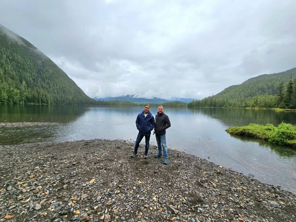 Cruising with Danny and Peter, Holland America Line, Westerdam, Ketchikan, Alaska, United States, Adventure History Thrills | A vibrant collage capturing the Ketchikan Adventure Tour in Alaska, featuring a dynamic log-rolling contest at the Great Alaskan Lumberjack Show with lumberjacks in plaid shirts balancing on a floating log, a rugged UTV navigating a muddy trail through the Tongass National Forest with George Inlet Fjords’ turquoise waters in view, a serene scenic cruise along the Inside Passage with a bald eagle soaring above mist-covered mountains, and a cozy scene at George Inlet Lodge with a rustic table set with craft beers, creamy crab chowder, hot Dungeness crab, and blueberry cheesecake. In the background, Ketchikan’s historic Creek Street showcases colorful buildings on stilts and a Tlingit totem pole, framed by lush greenery and rugged Alaskan peaks, embodying the city’s thrilling adventures and rich cultural heritage.