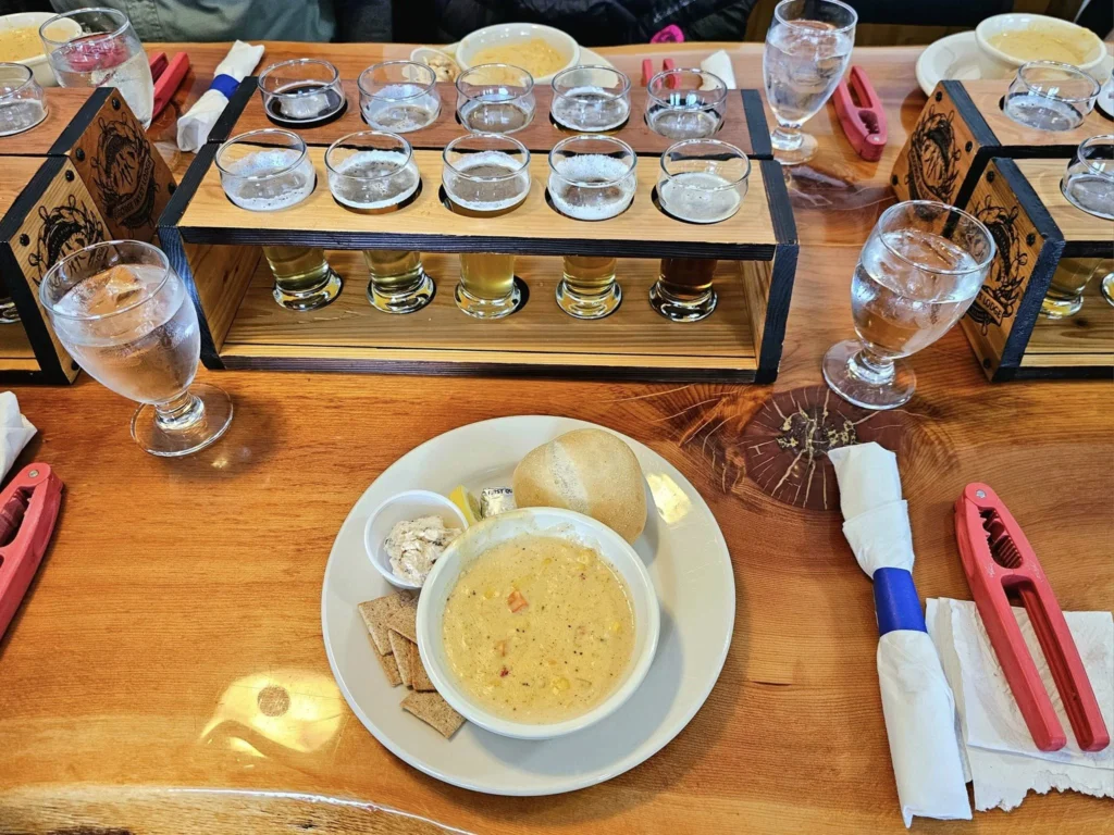 Cruising with Danny and Peter, Holland America Line, Westerdam, Ketchikan, Alaska, United States, Adventure History Thrills | A vibrant collage capturing the Ketchikan Adventure Tour in Alaska, featuring a dynamic log-rolling contest at the Great Alaskan Lumberjack Show with lumberjacks in plaid shirts balancing on a floating log, a rugged UTV navigating a muddy trail through the Tongass National Forest with George Inlet Fjords’ turquoise waters in view, a serene scenic cruise along the Inside Passage with a bald eagle soaring above mist-covered mountains, and a cozy scene at George Inlet Lodge with a rustic table set with craft beers, creamy crab chowder, hot Dungeness crab, and blueberry cheesecake. In the background, Ketchikan’s historic Creek Street showcases colorful buildings on stilts and a Tlingit totem pole, framed by lush greenery and rugged Alaskan peaks, embodying the city’s thrilling adventures and rich cultural heritage.