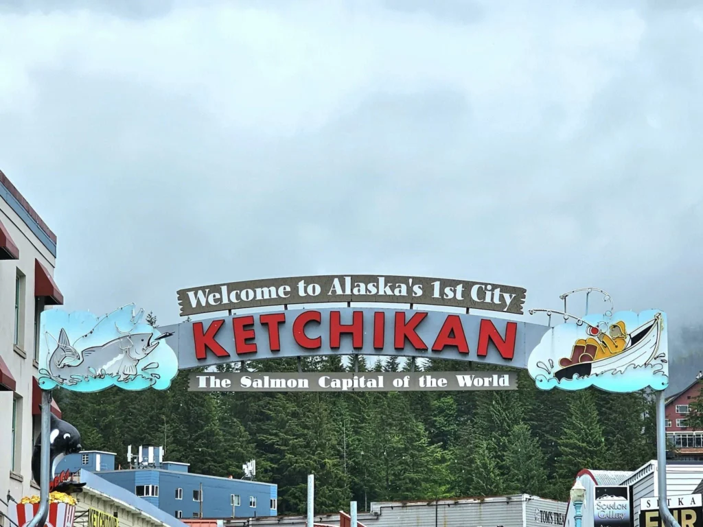 Cruising with Danny and Peter, Holland America Line, Westerdam, Ketchikan, Alaska, United States, Adventure History Thrills | A vibrant collage capturing the Ketchikan Adventure Tour in Alaska, featuring a dynamic log-rolling contest at the Great Alaskan Lumberjack Show with lumberjacks in plaid shirts balancing on a floating log, a rugged UTV navigating a muddy trail through the Tongass National Forest with George Inlet Fjords’ turquoise waters in view, a serene scenic cruise along the Inside Passage with a bald eagle soaring above mist-covered mountains, and a cozy scene at George Inlet Lodge with a rustic table set with craft beers, creamy crab chowder, hot Dungeness crab, and blueberry cheesecake. In the background, Ketchikan’s historic Creek Street showcases colorful buildings on stilts and a Tlingit totem pole, framed by lush greenery and rugged Alaskan peaks, embodying the city’s thrilling adventures and rich cultural heritage.