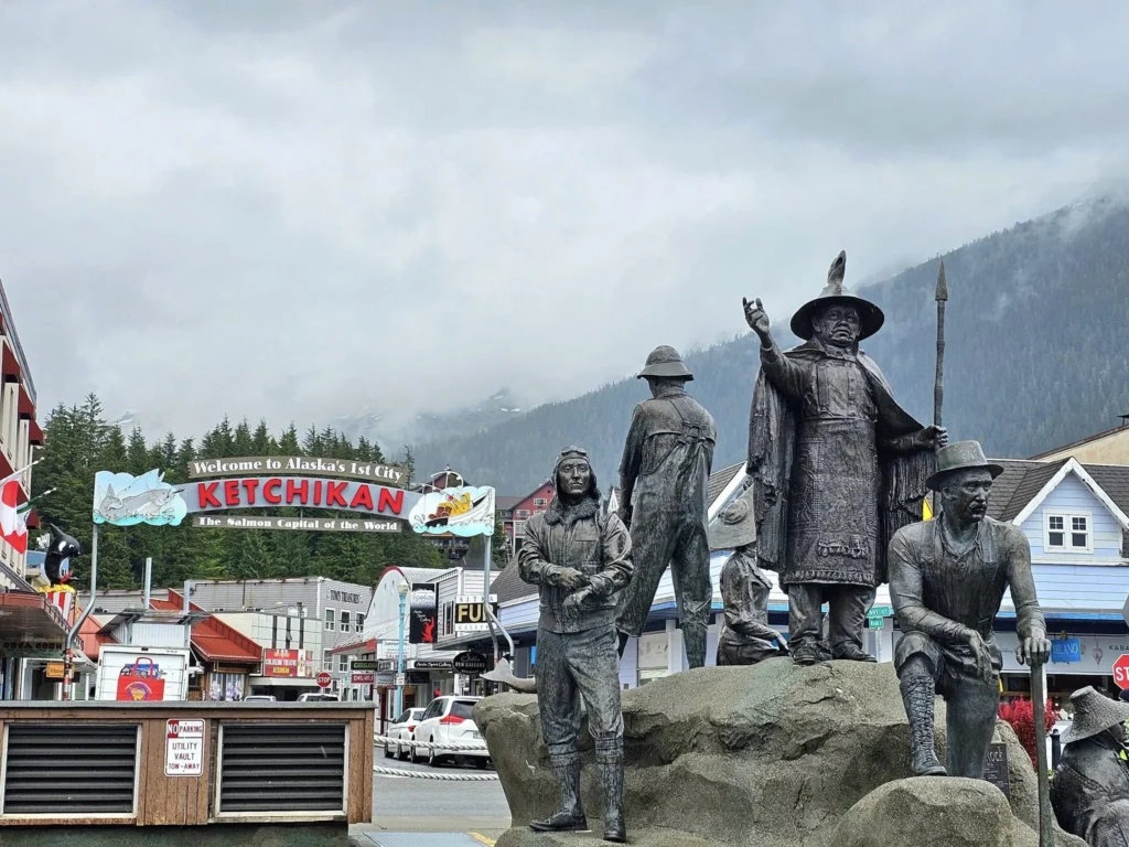 Cruising with Danny and Peter, Holland America Line, Westerdam, Ketchikan, Alaska, United States, Adventure History Thrills | A vibrant collage capturing the Ketchikan Adventure Tour in Alaska, featuring a dynamic log-rolling contest at the Great Alaskan Lumberjack Show with lumberjacks in plaid shirts balancing on a floating log, a rugged UTV navigating a muddy trail through the Tongass National Forest with George Inlet Fjords’ turquoise waters in view, a serene scenic cruise along the Inside Passage with a bald eagle soaring above mist-covered mountains, and a cozy scene at George Inlet Lodge with a rustic table set with craft beers, creamy crab chowder, hot Dungeness crab, and blueberry cheesecake. In the background, Ketchikan’s historic Creek Street showcases colorful buildings on stilts and a Tlingit totem pole, framed by lush greenery and rugged Alaskan peaks, embodying the city’s thrilling adventures and rich cultural heritage.
