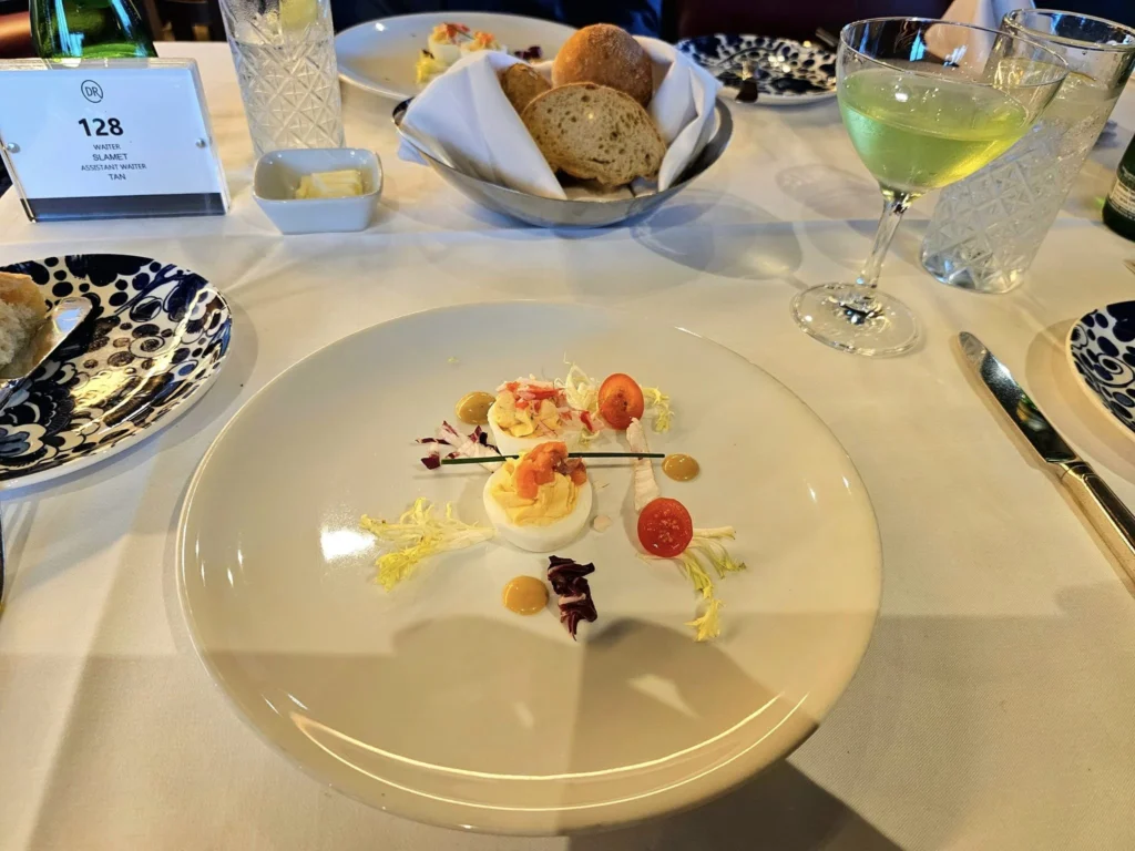 Cruising with Danny and Peter, Holland America Line, Westerdam, Ketchikan, Alaska, United States, Adventure History Thrills | A vibrant collage capturing the Ketchikan Adventure Tour in Alaska, featuring a dynamic log-rolling contest at the Great Alaskan Lumberjack Show with lumberjacks in plaid shirts balancing on a floating log, a rugged UTV navigating a muddy trail through the Tongass National Forest with George Inlet Fjords’ turquoise waters in view, a serene scenic cruise along the Inside Passage with a bald eagle soaring above mist-covered mountains, and a cozy scene at George Inlet Lodge with a rustic table set with craft beers, creamy crab chowder, hot Dungeness crab, and blueberry cheesecake. In the background, Ketchikan’s historic Creek Street showcases colorful buildings on stilts and a Tlingit totem pole, framed by lush greenery and rugged Alaskan peaks, embodying the city’s thrilling adventures and rich cultural heritage.