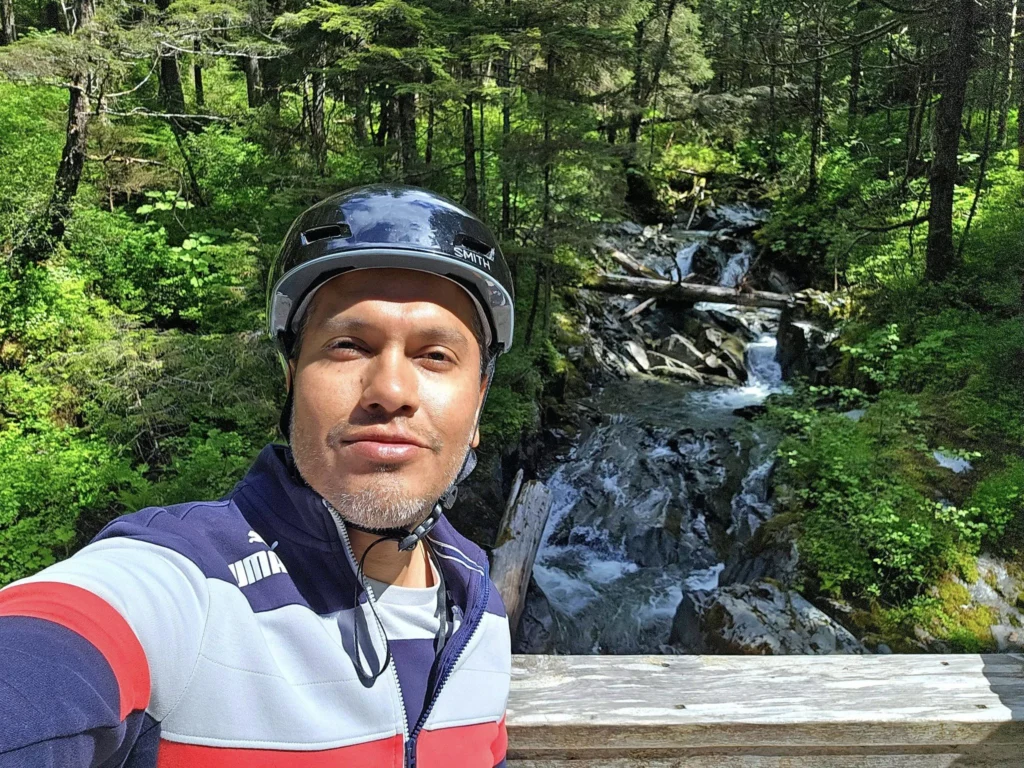 Cruising with Danny and Peter, Holland America Line, Westerdam, Sitka, Alaska, United States | Biking the scenic Sitka Cross Trail through lush Alaskan forests, capturing Sitka's natural beauty and outdoor adventure; a whale breaching in Whale Park, showcasing Sitka Alaska's wildlife; a majestic eagle soaring above, symbolizing the rich wildlife; and an intricate Tlingit totem pole representing the cultural heritage of Sitka, Alaska, all set against the stunning coastal landscape of this Alaskan gem.