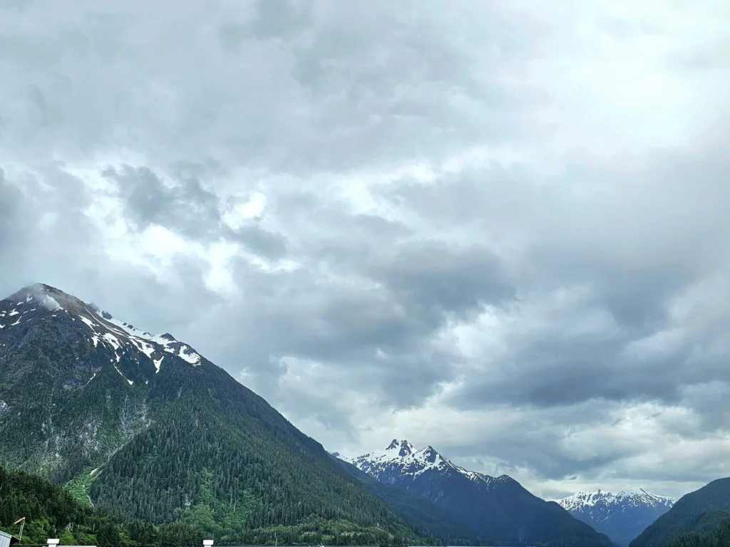 Cruising with Danny and Peter, Holland America Line, Westerdam, Sitka, Alaska, United States | Biking the scenic Sitka Cross Trail through lush Alaskan forests, capturing Sitka's natural beauty and outdoor adventure; a whale breaching in Whale Park, showcasing Sitka Alaska's wildlife; a majestic eagle soaring above, symbolizing the rich wildlife; and an intricate Tlingit totem pole representing the cultural heritage of Sitka, Alaska, all set against the stunning coastal landscape of this Alaskan gem.