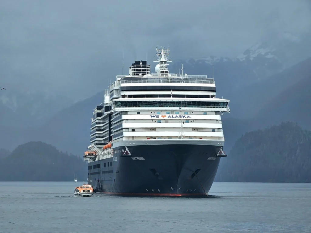 Cruising with Danny and Peter, Holland America Line, Westerdam, Sitka, Alaska, United States | Biking the scenic Sitka Cross Trail through lush Alaskan forests, capturing Sitka's natural beauty and outdoor adventure; a whale breaching in Whale Park, showcasing Sitka Alaska's wildlife; a majestic eagle soaring above, symbolizing the rich wildlife; and an intricate Tlingit totem pole representing the cultural heritage of Sitka, Alaska, all set against the stunning coastal landscape of this Alaskan gem.